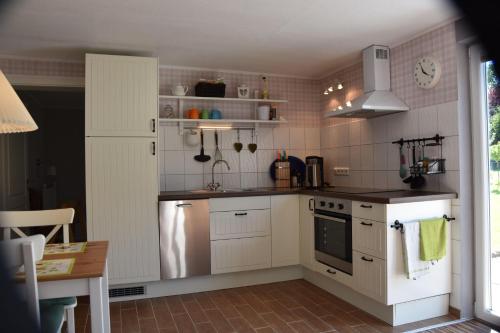 a kitchen with white cabinets and a sink and a refrigerator at Bungalow-Gartenzauber in Grube