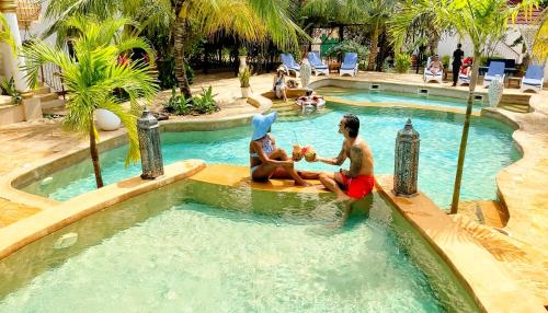 two people sitting in a pool at a resort at Kibanda Natural Kendwa Villa in Kendwa