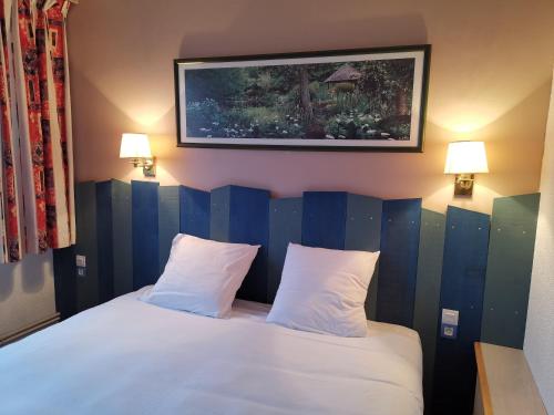 um quarto com uma cama com duas almofadas brancas em Hôtel Le Sully La Roche Sur Yon em La Roche-sur-Yon