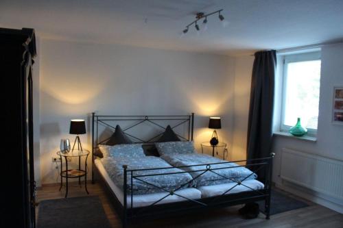 Un dormitorio con una cama y dos lámparas y una ventana. en Ferienwohnung-Villa-Helene, en Blankenburg