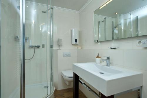 a white bathroom with a sink and a shower at Duenenhof-zum-Kronprinzen-Appm-60 in Wenningstedt