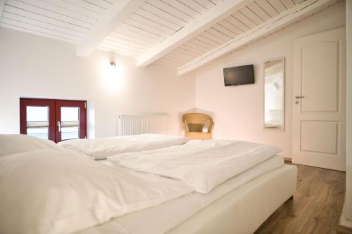 a white bedroom with two white beds and a tv at Haus Steuerrad in Stralsund