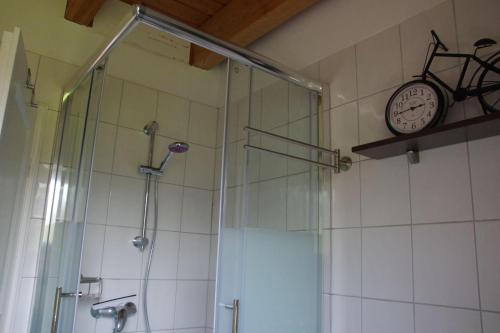 a bathroom with a shower and a clock on the wall at Luettje-Glueck-2 in Pogum