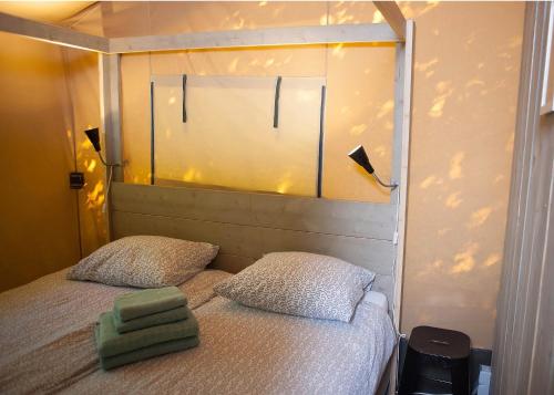een kleine slaapkamer met een bed met 2 kussens bij Glamping Nunspeet Veluwe in Nunspeet