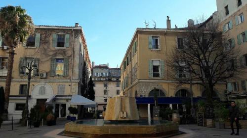 une fontaine au milieu d'une ville avec des bâtiments dans l'établissement Le cocon de Louise-Vieux Port, à Marseille