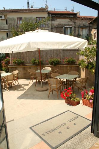 a table and chairs under an umbrella on a patio at Hotel Reginella in SantʼAgata sui Due Golfi