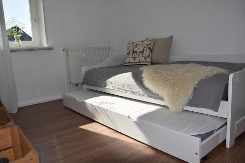 a bed with a white frame with a fur blanket on it at Moewe in Landkirchen