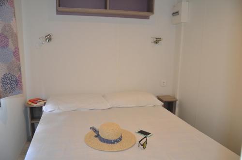 kapelusz i okulary przeciwsłoneczne siedzące na łóżku w obiekcie Happy Camp mobile homes in Camping Amadria Park Camping Trogir w mieście Seget Vranjica