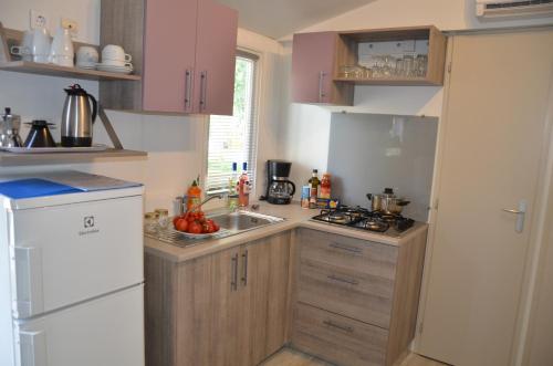 a kitchen with pink cabinets and a white refrigerator at Happy Camp mobile homes in Camping Amadria Park Camping Trogir in Seget Vranjica
