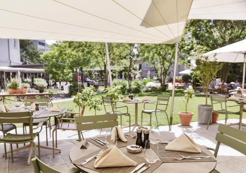 a patio area with tables, chairs and umbrellas at Swissôtel Kursaal Bern in Bern