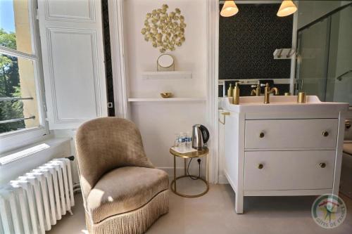 a bathroom with a sink and a chair and a mirror at Château du Golf de la Freslonnière in Le Rheu
