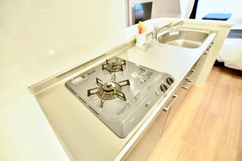 a kitchen with a stove and a sink at Riverside Inn Hakata in Fukuoka
