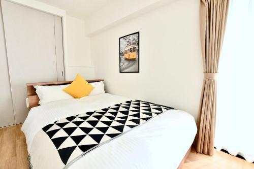 a bedroom with a bed with a black and white comforter at Riverside Inn Hakata in Fukuoka