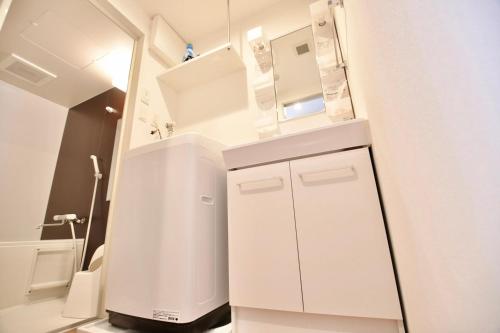a small bathroom with white cabinets and a sink at Riverside Inn Hakata in Fukuoka