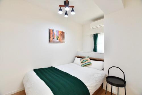 a bedroom with a white bed and a black chair at Riverside Inn Hakata in Fukuoka