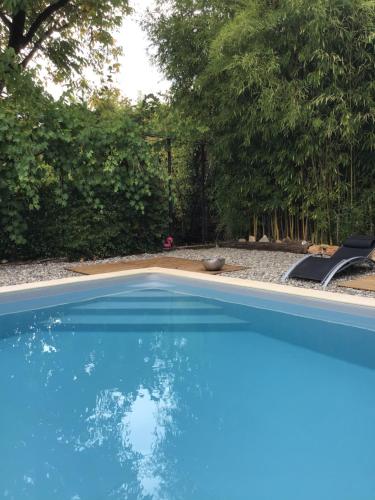 a blue swimming pool with a chair and trees at Villa Léovil in Saint-Pompont