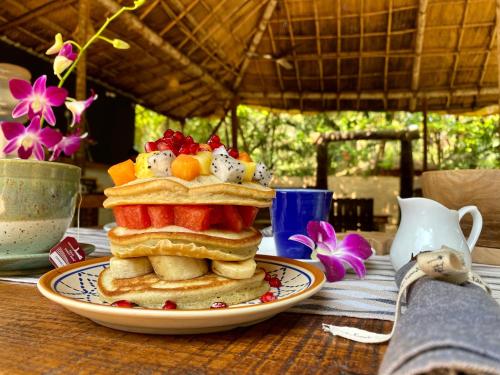 una pila de panqueques en un plato en una mesa en Palm Forest Palolem en Palolem