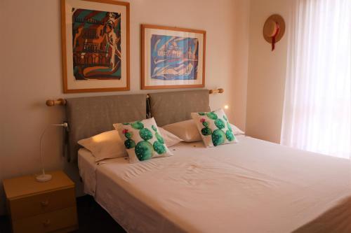 a bedroom with a white bed with green pillows at Appartamenti Valbella in Bibione