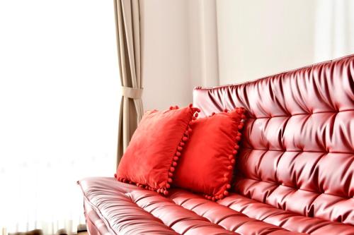 a red leather couch with two red pillows on it at Riverside Inn Hakata in Fukuoka