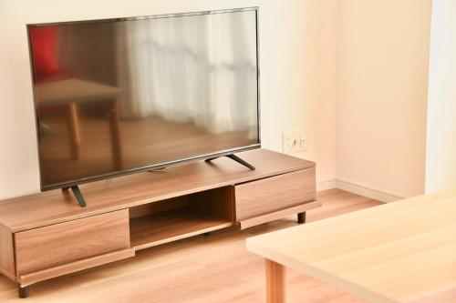 a flat screen tv sitting on a wooden entertainment center at Riverside Inn Hakata in Fukuoka