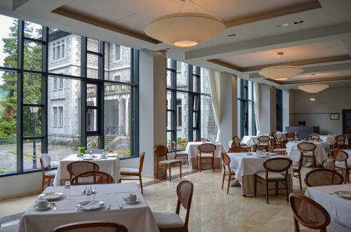a restaurant with tables and chairs and large windows at Parador de Limpias in Limpias