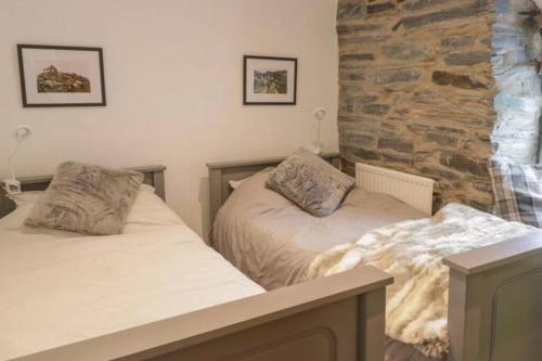 a bedroom with two beds and a stone wall at Pen y Cwm in Penmachno