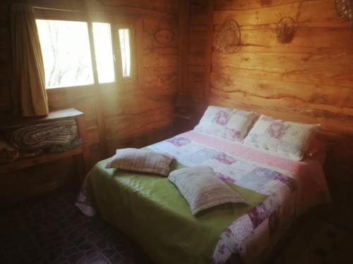 a bedroom with a bed in a log cabin at Cabañas Monje in Tandil