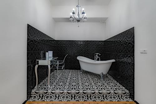 La salle de bains est pourvue d'une baignoire, d'une table et d'un lustre. dans l'établissement Rezidence Znojmo, à Znojmo