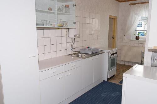 ヴィーク・アウフ・リューゲンにあるPreisguenstige-und-gemuetliche-Ferienwohnung-am-Wieker-Boddenの白いキッチン(シンク、コンロ付)