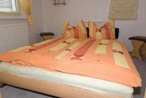 ヴィーク・アウフ・リューゲンにあるPreisguenstige-und-gemuetliche-Ferienwohnung-am-Wieker-Boddenの大型ベッド1台(ベッドルーム内にオレンジ色の掛け布団付)