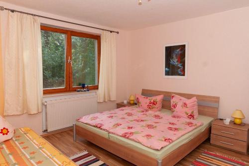 Schlafzimmer mit einem Bett mit rosa Bettwäsche und einem Fenster in der Unterkunft Geschmackvoll ausgestattete Ferienwohnung für 4 Personen in Sagard