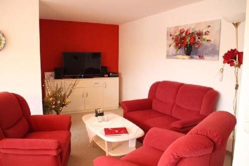 a living room with red chairs and a tv at Nordsee-Residenz-City-App-18 in Westerland