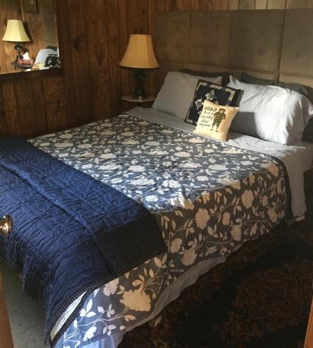 ein Schlafzimmer mit einem Bett mit einer blauen Decke in der Unterkunft Redfish Cottages in Delta