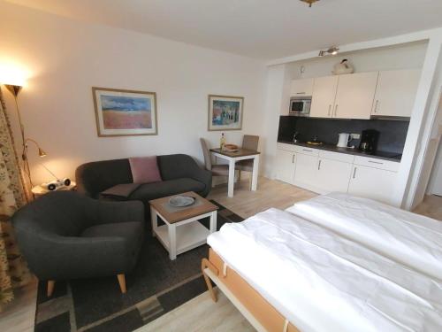 ein Schlafzimmer mit einem Bett und einem Sofa sowie eine Küche in der Unterkunft Sylter Sprotte "Haus Ornum" in Westerland
