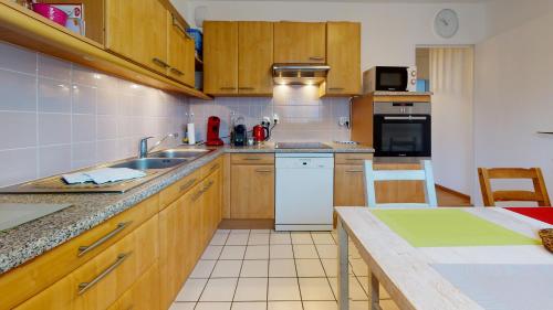 une cuisine avec des armoires en bois et un réfrigérateur blanc dans l'établissement Gîte Saint Josse 3 chambres, à Colmar