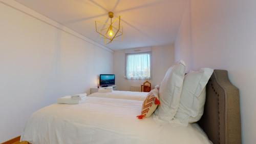 1 dormitorio con 1 cama blanca grande con lámpara de araña en Gîte Saint Josse 3 chambres en Colmar