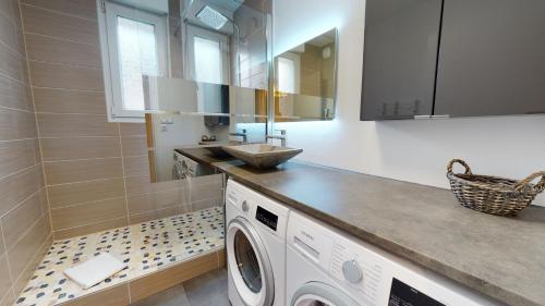 une salle de bain avec une machine à laver et un lavabo dans l'établissement Gîte Saint Josse 3 chambres, à Colmar