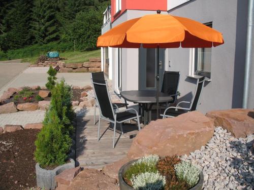 a patio with a table and chairs under an umbrella at Ferienwohnung-am-Foerstereck in Freudenstadt