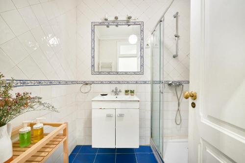 La salle de bains blanche est pourvue d'un lavabo et d'un miroir. dans l'établissement Spacious Bairro Alto Apartment With Courtyard, By TimeCooler, à Lisbonne