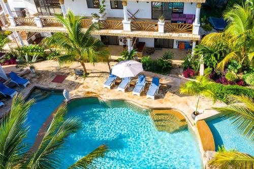 an aerial view of a resort pool with chairs and an umbrella at Kibanda Natural Kendwa Villa in Kendwa