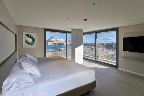 a bedroom with a large white bed and large windows at Hotel & Spa Castillo de Peñíscola 4* Sup in Peniscola