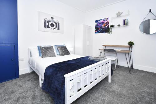 Schlafzimmer mit einem weißen Bett und einem Schreibtisch in der Unterkunft Townhouse @ 42 Minshull New Road Crewe in Crewe