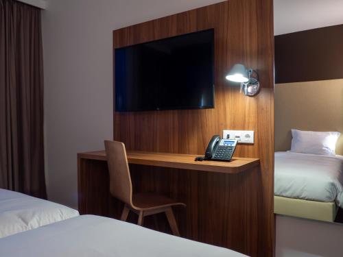 a hotel room with a desk with a television and a phone at Campanile Caldas da Rainha in Caldas da Rainha