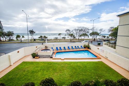 a swimming pool with chairs and the ocean in the background at The Shore Apartments - Beachfront in Gold Coast