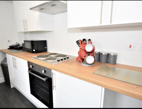 a kitchen with a counter top with a stove top oven at Townhouse @ Birks Street Stoke in Stoke on Trent