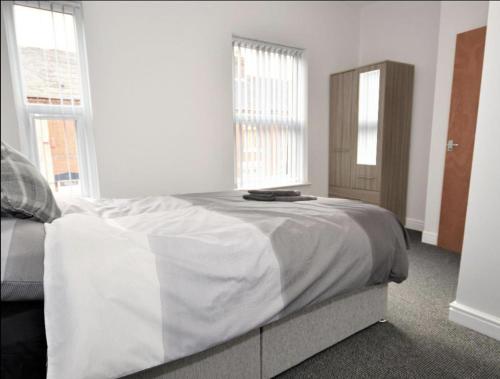 a white bedroom with a bed and two windows at Townhouse @ Birks Street Stoke in Stoke on Trent