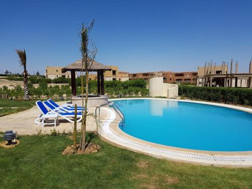 a swimming pool with two chairs and a gazebo at Byoum Vacation House in Fayoum