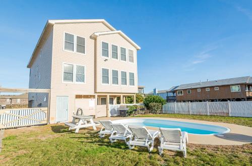 a house with chairs and a swimming pool at Sea Sun Greetings - Kitty Hawk MP 2.5, Ocean Views, Direct Beach Access, Pool, Hot Tub, Pets OK in Kitty Hawk