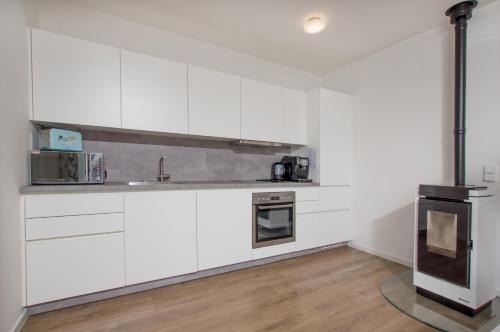a kitchen with white cabinets and a stove at Lipno Club in Frymburk