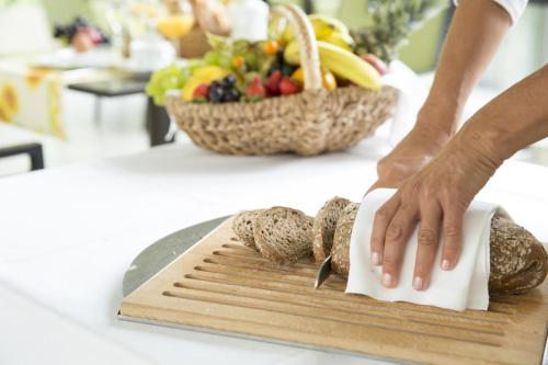 a person cutting bread on a cutting board on a counter at Johannesbad Hotel Füssinger Hof in Bad Füssing